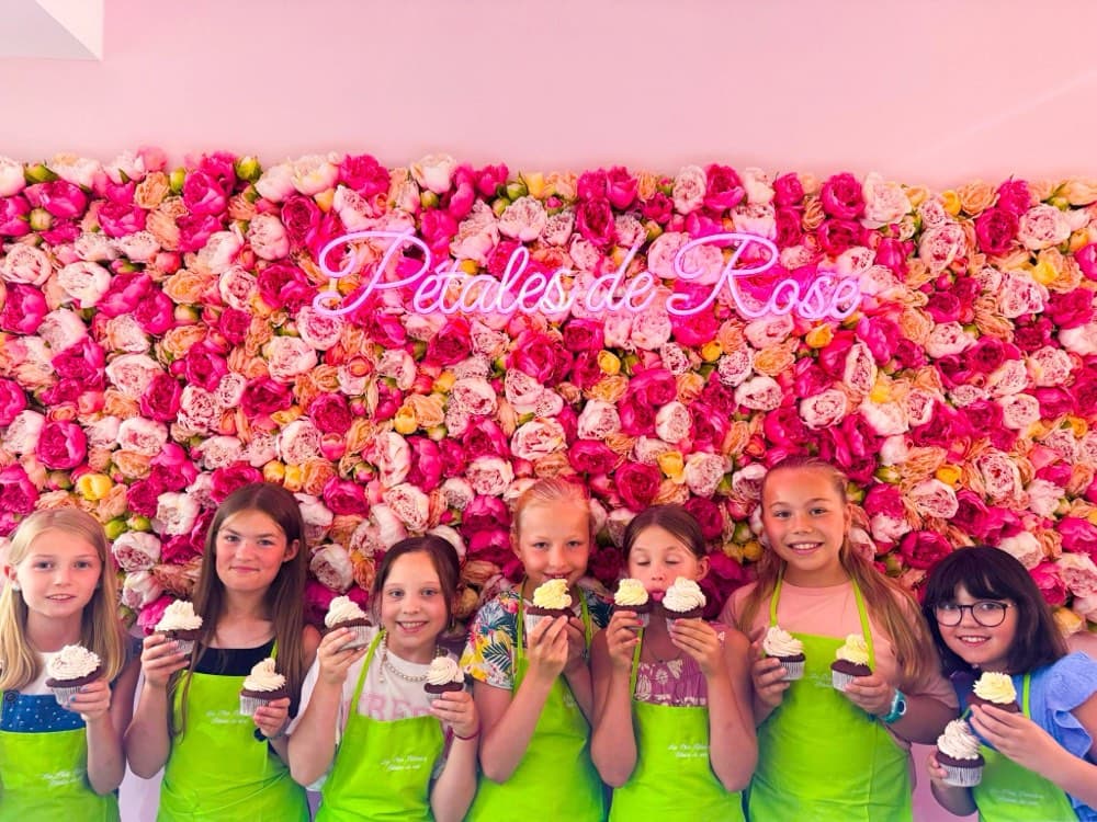 Groupe d'enfants montrant leurs cupcakes au mur de fleurs